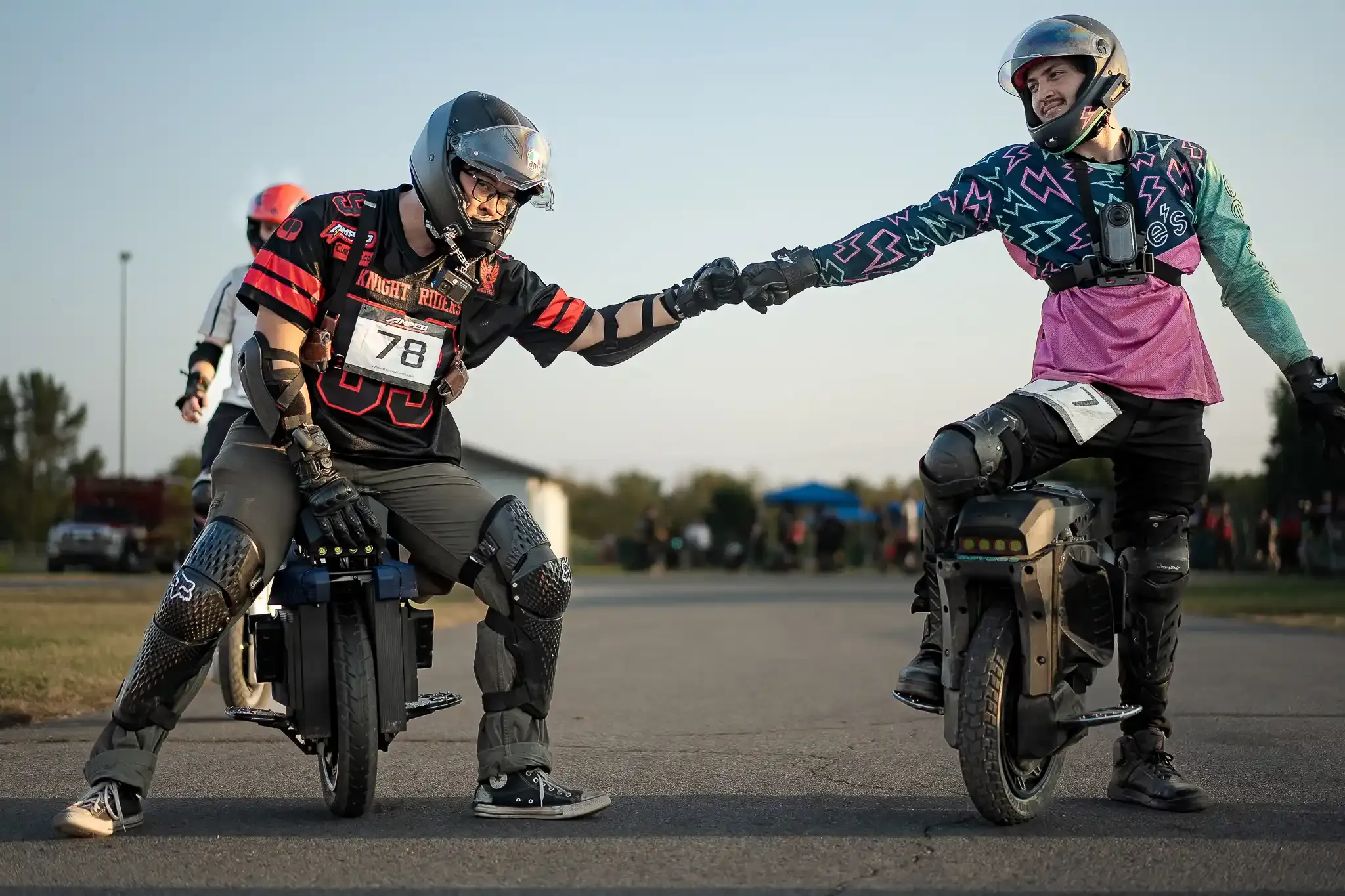 Two riders on electric unicycles bump fists before a race