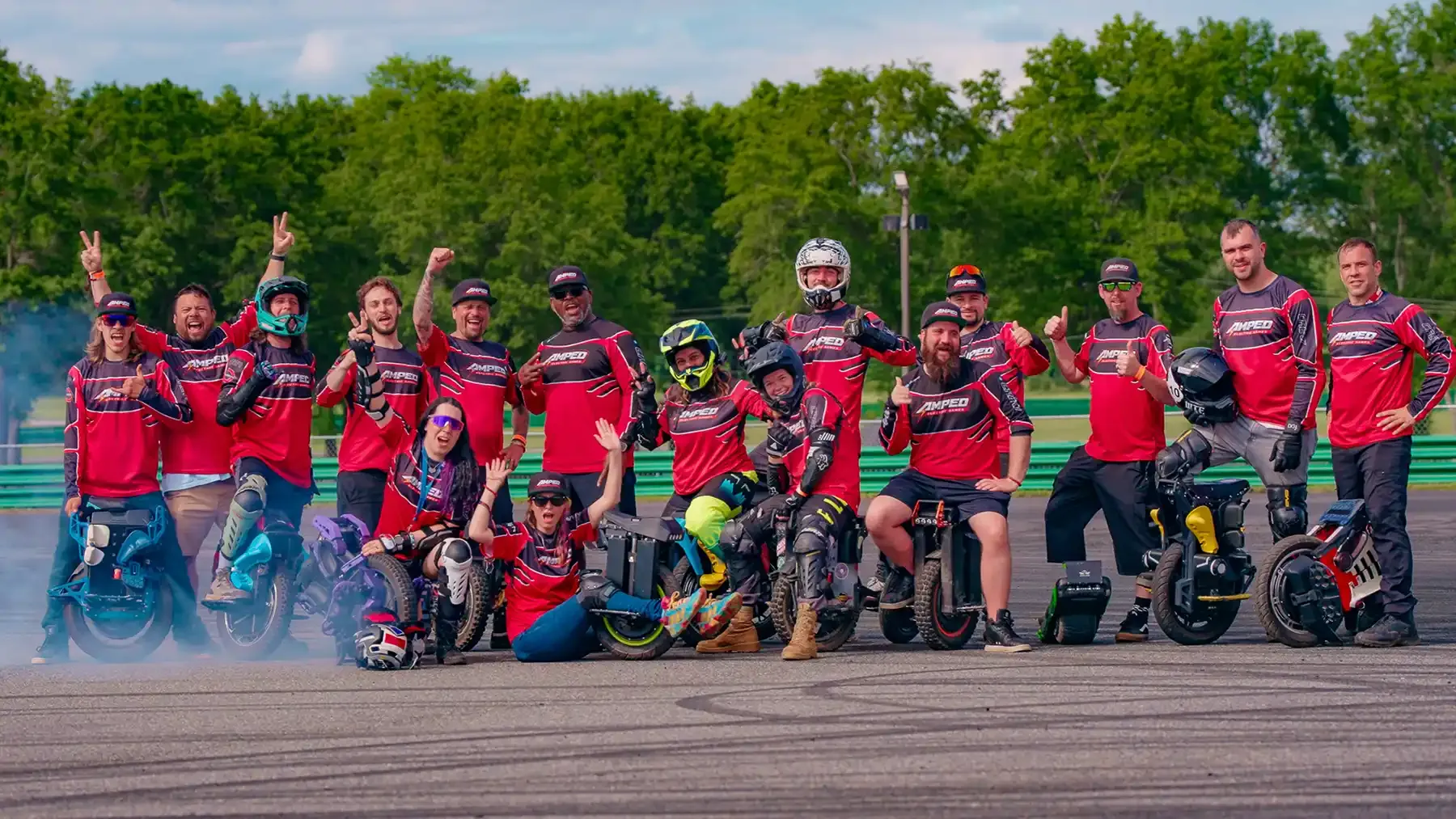 The Electric Angels team in matching red and black jerseys, posing with their electric unicycles on a race track
